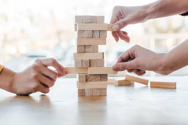 KYIV, UKRAINE - NOVEMBER 22, 2019: cropped view of three women playing blocks wood tower game at home — Stock Photo