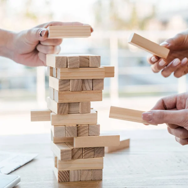 KYIV, UCRÂNIA - NOVEMBRO 22, 2019: visão cortada de amigos jogando blocos de jogo de torre de madeira — Fotografia de Stock