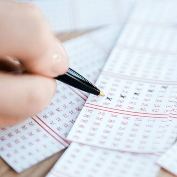 Крупным планом женщин, маркирующих номера на лотерейных билетах на столе — стоковое фото