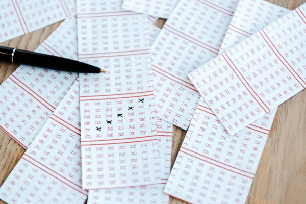 Vista superior da caneta perto de bilhetes de loteria marcados na mesa de madeira — Fotografia de Stock
