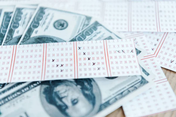 Messa a fuoco selettiva dei biglietti della lotteria contrassegnati vicino alle banconote in dollari sul tavolo — Foto stock
