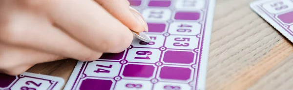 Panoramic shot of woman holding coin and scratching lottery ticket — Stock Photo