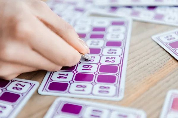 Cropped view of woman holding coin and scratching lottery ticket — Stock Photo