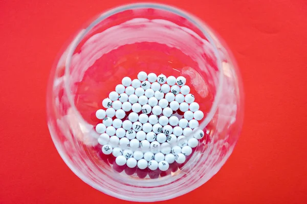 Top view of glass bowl with lottery balls isolated on red — Stock Photo
