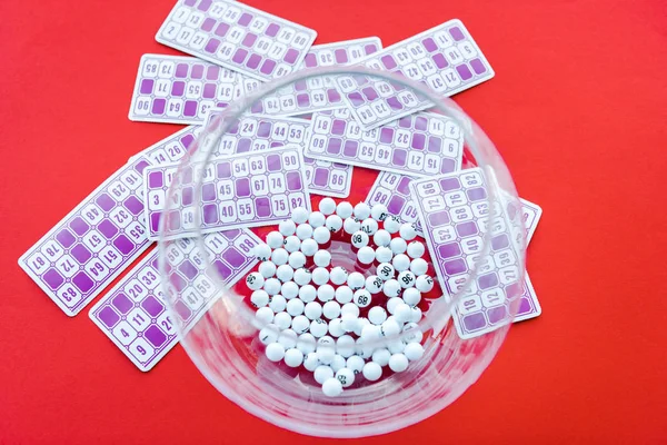 Vista superior del tazón con bolas cerca de billetes de lotería aislados en rojo — Stock Photo