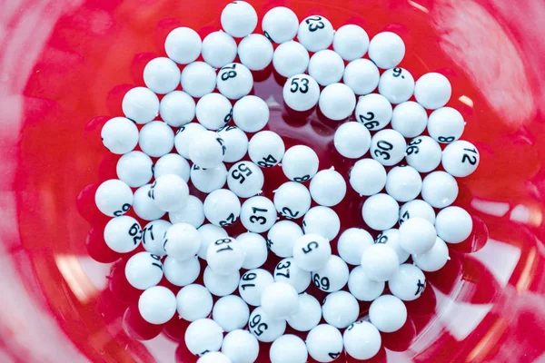 Close up of bowl with balls near lottery tickets isolated on red — Stock Photo