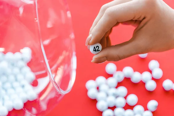 Cropped view of woman holding number near glass bowl isolated on red — Stock Photo