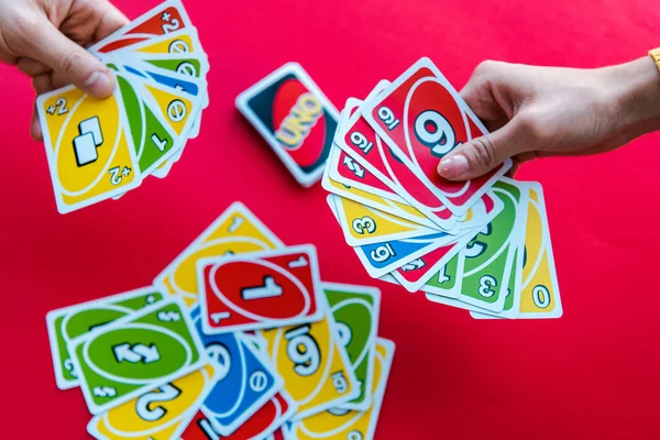 KYIV, UKRAINE - NOVEMBER 22, 2019: top view of friends playing uno playing cards isolated on red — Stock Photo