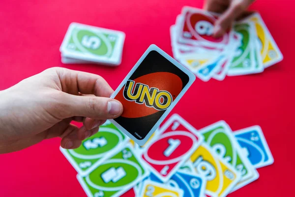 KYIV, UKRAINE - NOVEMBER 22, 2019: cropped view of man holding uno playing card isolated on red — Stock Photo