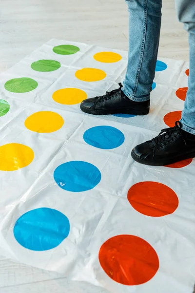 KYIV, UKRAINE - NOVEMBER 22, 2019: cropped view of man in jeans standing on twister game — Stock Photo