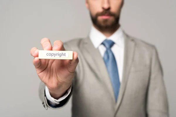 Partial view of businessman showing wooden block with word copyright isolated on grey — Stock Photo