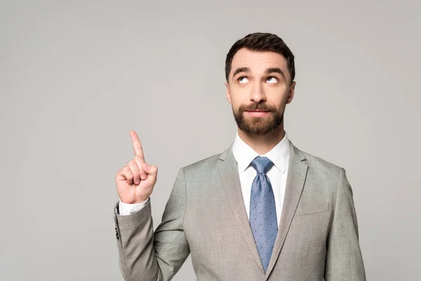 Uomo d'affari sorridente guardando altrove, mostrando idea gesto isolato su grigio — Foto stock