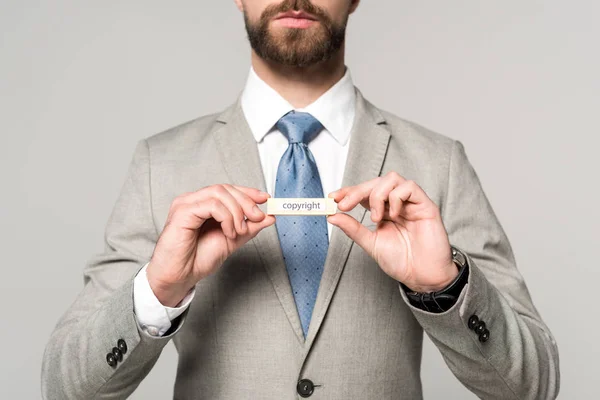 Частковий вид бізнесмена, що показує дерев'яний блок зі словом авторське право ізольовано на сірому — стокове фото