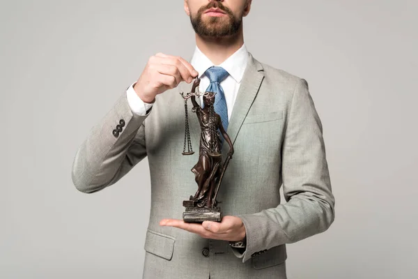 Vista parcial del abogado sosteniendo la estatua de themis aislado en gris - foto de stock