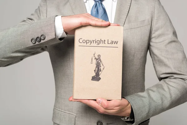 Cropped view of lawyer holding book with copyright law title isolated on grey — Stock Photo