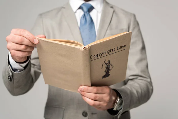 Cropped view of lawyer holding book with copyright law title isolated on grey — Stock Photo