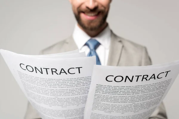Обрезанный вид улыбающийся бизнесмен reding контракты изолированы на серый — стоковое фото