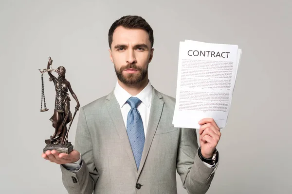 Confident lawyer holding contract and themis statue while looking at camera isolated on grey — Stock Photo