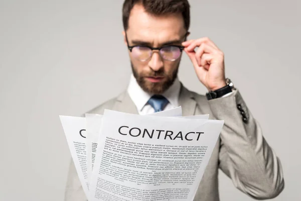 Серйозний бізнесмен в окулярах дивиться на контракти ізольовані на сірому — стокове фото