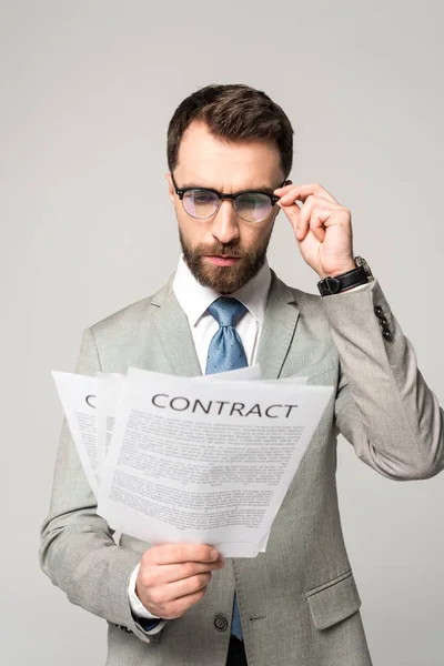 Serious businessman in glasses reading contract isolated on grey — Stock Photo