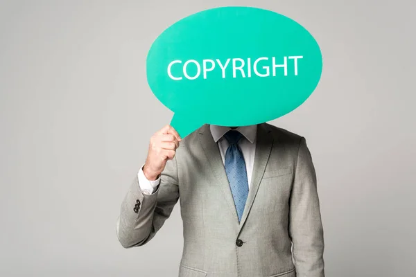 Businessman obscuring face with thought bubble with copyright inscription isolated on grey — Stock Photo