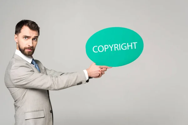 Serio uomo d'affari con bolla di pensiero con iscrizione sul copyright isolata su grigio — Foto stock