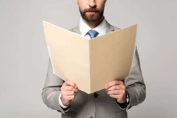 Vista parcial del empresario sosteniendo la carpeta de papel aislada en gris - foto de stock