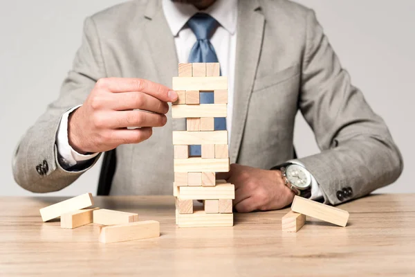 Vista recortada de hombre de negocios jugando bloques torre de madera juego aislado en gris - foto de stock