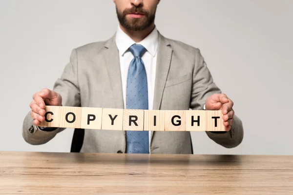 Cropped view of businessman holding wooden cubes with word copyright isolated on grey — Stock Photo