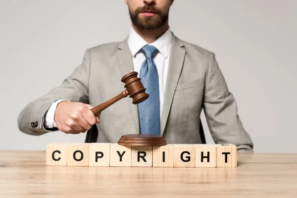 Cropped view of judge holding gavel near wooden cubes with copyright inscription isolated on grey — Stock Photo