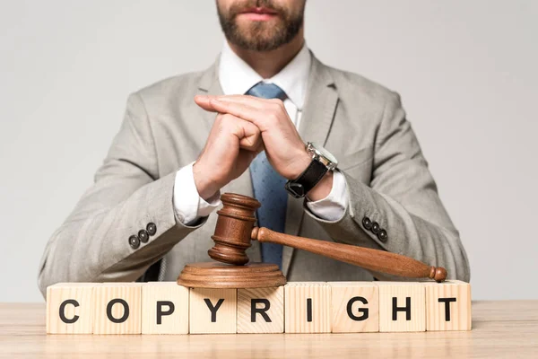 Vista parziale dell'avvocato vicino a martelletto e cubi di legno con iscrizione sul copyright isolata su grigio — Foto stock