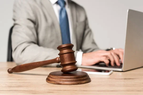 Selective focus of gavel near lawyer working at laptop isolated on grey — Stock Photo