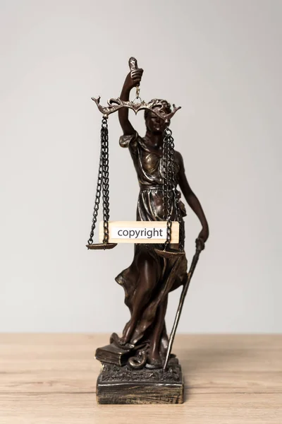 Statue themis et bloc de bois avec copyright mot sur écailles sur bureau en bois isolé sur gris — Photo de stock