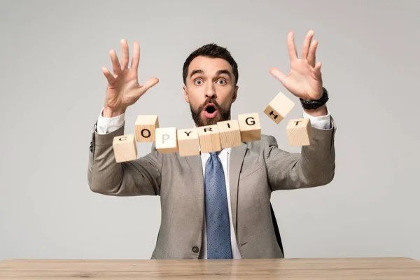Cropped view of shocked businessman near falling cubes with copyright lettering isolated on grey — Stock Photo