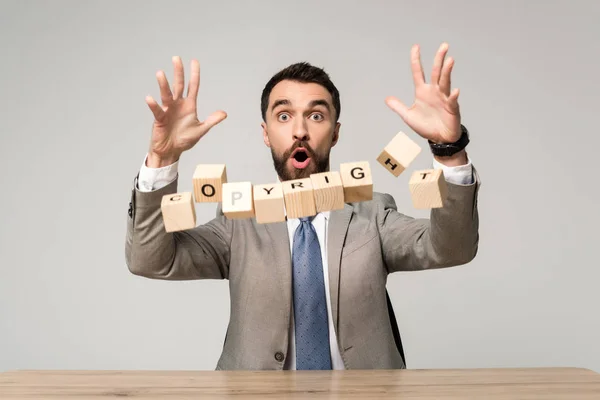 Abgeschnittene Ansicht eines schockierten Geschäftsmannes in der Nähe herabfallender Würfel mit urheberrechtlichem Schriftzug isoliert auf grau — Stockfoto