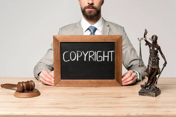 Cropped view of lawyer near gavel, themis statue and chalkboard with word copyright isolated on grey — Stock Photo