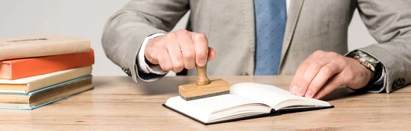 Обрезанный вид юриста, помещающего штамп в блокнот изолированный на сером, панорамный снимок — стоковое фото