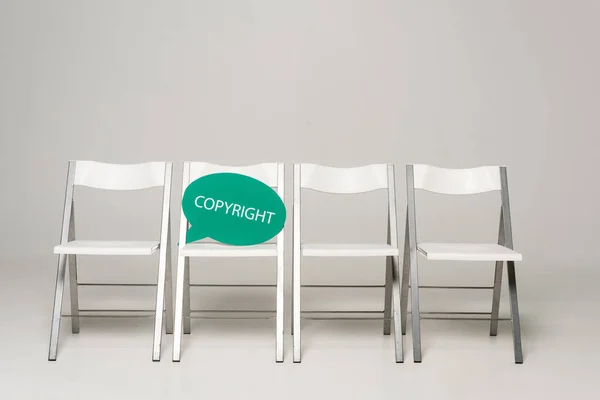 Row of chairs and thought bubble with copyright inscription on grey background — Stock Photo