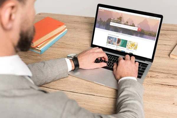 KYIV, UKRAINE - NOVEMBER 25, 2019: cropped view of businessman using laptop with Shutterstock website on screen isolated on grey — Stock Photo