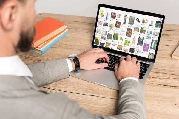 KYIV, UKRAINE - NOVEMBER 25, 2019: cropped view of businessman using laptop with Pinterest website on screen isolated on grey — Stock Photo