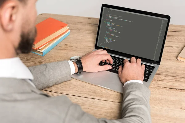 KYIV, UKRAINE - NOVEMBER 25, 2019: partial view of programmer using laptop with Javascript on screen isolated on grey — Stock Photo