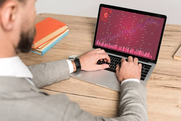 Partial view of businessman using laptop with graphs and charts on screen isolated on grey — Stock Photo