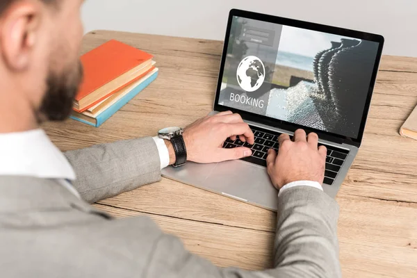 Abgeschnittene Ansicht von Geschäftsmann mit Laptop mit Buchungswebseite auf dem Bildschirm isoliert auf grau — Stockfoto