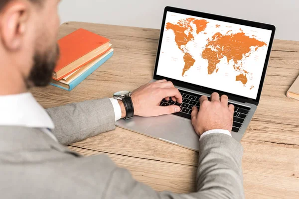 Cropped view of businessman using laptop with world map on screen isolated on grey — Stock Photo