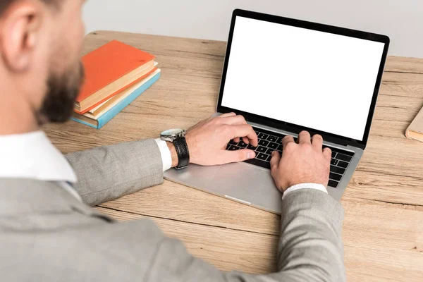 Vue recadrée de l'homme d'affaires en utilisant un ordinateur portable avec écran blanc isolé sur gris — Photo de stock