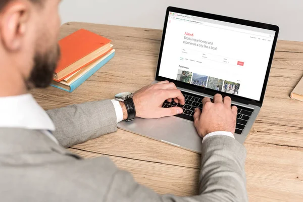 KYIV, UKRAINE - NOVEMBER 25, 2019: cropped view of businessman using laptop with Airbnb website on screen isolated on grey — Stock Photo