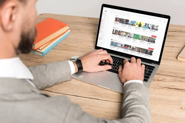 KYIV, UKRAINE - NOVEMBER 25, 2019: cropped view of businessman using laptop with Youtube website on screen isolated on grey — Stock Photo