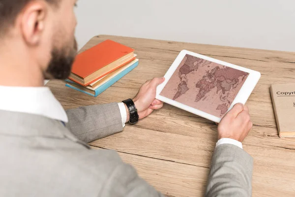 Vista parcial del hombre de negocios utilizando tableta digital con mapa del mundo en pantalla aislada en gris - foto de stock