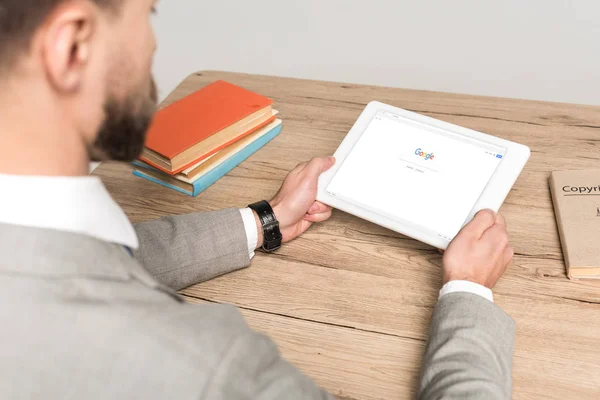 KYIV, UKRAINE - NOVEMBER 25, 2019: cropped view of businessman using digital tablet with Google on screen isolated on grey — Stock Photo