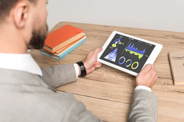 Visione parziale dell'uomo d'affari che utilizza tablet digitale con infografiche di marketing su schermo isolato su grigio — Foto stock